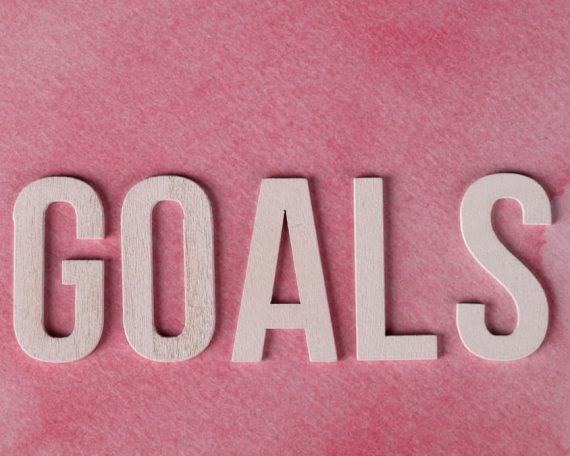 Motivational word 'GOALS' on a pink watercolor background for inspiration.